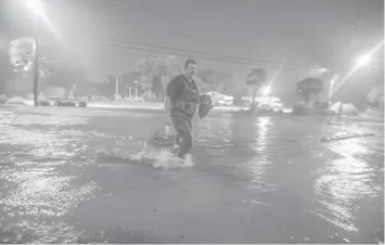  ?? AGENCE FRANCE PRESSE ?? Lanny Dean, from Tulsa, Oklahoma, takes video as he wades along a flooded Beach Boulevard next to Harrahs Casino as the eye of Hurricane Nate pushes ashore in Biloxi, Mississipp­i.