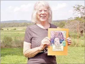  ?? RACHEL DICKERSON/MCDONALD COUNTY PRESS ?? Carol Klein holds up a copy of her book, “Buffalo Children: How I Became a Buffalo Mother” at her buffalo ranch in Jane.