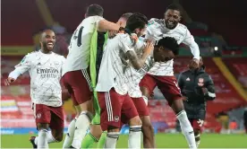  ?? Photograph: Simon Stacpoole/Offside/Getty Images ?? Arsenal players crowd Joe Willock as they celebrate the midfielder scoring the winning penalty in the shootout at Liverpool.