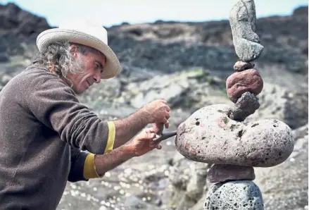  ??  ?? Balancing act: A stone stacking artist adding finishing touches to his sculpture. — AFP
