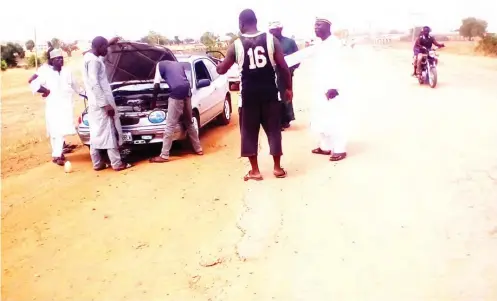  ??  ?? A faulty vehicle and stranded commuters on the Jega-Yauri road