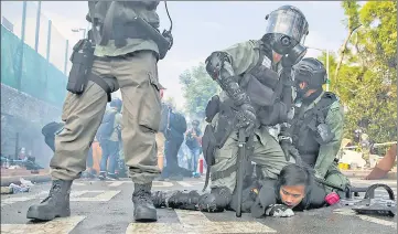  ?? A riot police officer detains a student during clashes in Hong Kong while another cop stands guard. AP ??