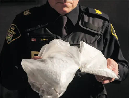  ?? CHRIS YOUNG / THE CANADIAN PRESS ?? An Ontario Provincial Police officer displays bags containing the deadly opioid fentanyl at a news conference in Vaughan, Ont., on Thursday. A total of 18 people were arrested in raids across Ontario and Quebec.