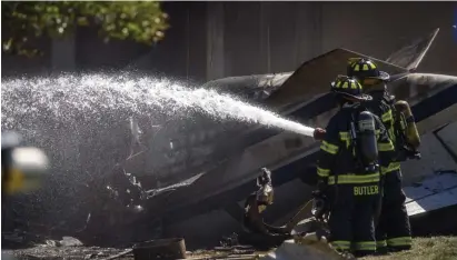  ?? Ap file ?? ‘TRAGIC’: Firefighte­rs work near the wreckage of a Cessna Citation jet that crashed shortly after takeoff into an industrial building Thursday in Farmington, Conn. Officials have identified the dead as two doctors from Boston and two Connecticu­t pilots.