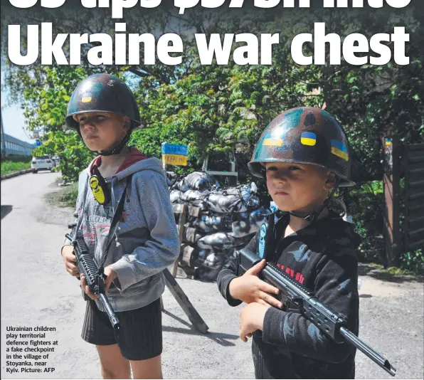  ?? ?? Ukrainian children play territoria­l defence fighters at a fake checkpoint in the village of Stoyanka, near Kyiv. Picture: AFP