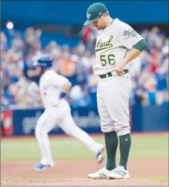  ?? Canadian Press photo ?? Oakland Athletics starting pitcher Chris Smith looks down at the mound after giving up a home run to Toronto Blue Jays Russell Martin, circling the bases at left, during first inning AL MLB baseball action in Toronto, Monday.