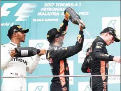  ?? AFP ?? Red Bull’s Max Verstappen (right) is sprayed with champagne by third-placed teammate Daniel Ricciardo and second-placed Mercedes driver Lewis Hamilton (left) after winning the Malaysia Grand Prix.