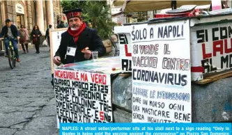  ??  ?? NAPLES: A street seller/performer sits at his stall next to a sign reading “Only in Naples is being sold the vaccine against the coronaviru­s” on Piazza San Domenico Maggiore in Naples. — AFP