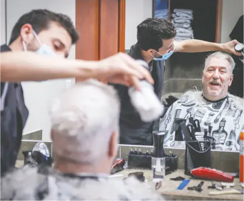  ?? Jef Mcintosh / the cana dian pres ?? Salim Alhaj cuts the hair of client John Gee of Calgary at his Kingsview Barbershop on its reopening Thursday in
Airdrie. “I feel lighter, lighter. I can feel the wind on my head,” Gee said a half-hour after he got into the chair.