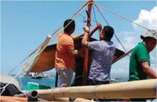  ?? Oceans photo) (USAID ?? Representa­tives of the United States Agency for Internatio­nal Developmen­t’s Oceans project and Futuristic Aviation and Maritime Enterprise, Inc. install transponde­rs on a small-scale vessel outside of General Santos City.