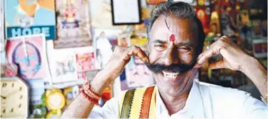  ?? Agence France-presse ?? ↑
K. Padmarajan twirls his moustache while posing for a photograph at his office in Mettur.