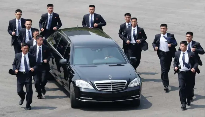  ?? © afp ?? Een dozijn NoordKoraa­nse bodyguards joggend naast de limousine van leider Kim Jongun.