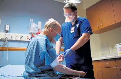  ?? Photos by Hyoung Chang, The Denver Post ?? State Rep. Kyle Mullica, D-Northglenn, right, checks the blood pressure of Randall Bargman in the emergency room at Presbyteri­an St. Luke's Medical Center in Denver on Dec. 5. Mullica works as a trauma nurse at the hospital.