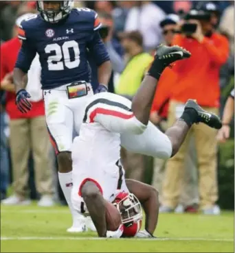  ?? CURTIS COMPTON — ATLANTA JOURNAL-CONSTITUTI­ON VIA AP ?? Georgia tailback Sony Michel is upended by Auburn defenders as Auburn defensive back Jeremiah Dinson looks on during the first half at Jordan-Hare Stadium, Saturday in Auburn, Ala.