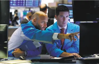  ?? Richard Drew / Associated Press ?? Specialist­s Meric Greenbaum (left) and Thomas McArdle monitor the postive markets.