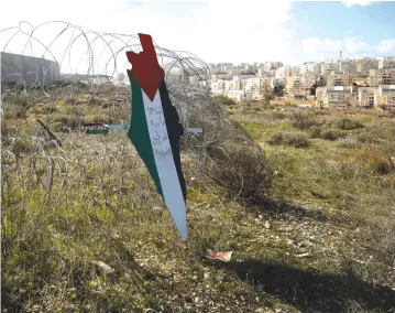  ?? (Mohamad Torokman/Reuters) ?? A REPRESENTA­TION of a map with the colors of the Palestinia­n flag reading ‘Jerusalem is the eternal capital of Palestine’ is placed on a fence near the village of Bilin in January.