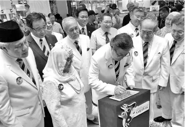  ??  ?? Abang Johari signing the plaque to symbolical­ly officiate the ‘Ibu Pertiwiku Exhibition’. Looking on are Juma’ani (second left), Uggah (second right), Awang Tengah (left), Morshidi (back row, second right), Abdul Karim (back row, left), Dr Sim (right)...