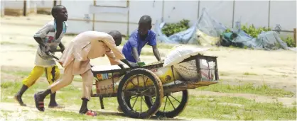  ??  ?? MAIDUGURI: Children displaced by Islamist extremists wheel food handed out to them at the Bakassi camp in Maiduguri, Nigeria. — AP