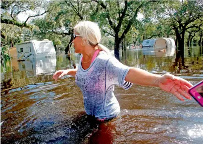  ?? AFP ?? Shelly Hughes hands her cell phone back to her daughter so she can go deeper into the water as the pair make their way through the flooded campground to check on their camper at the Peace River Campground in the wake of Hurricane Irma in Arcadia,...