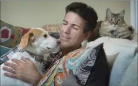  ?? WASHINGTON POST PHOTO — LINDA DAVIDSON ?? Humane Society executive Wayne Pacell at home with his dog Lily and cat, Zoe; research has shown that when humans interact with dogs, oxytocin levels increase in both species.