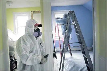  ?? Chitose Suzuki Associated Press ?? SINCE THE Environmen­tal Protection Agency’s rules for lead inside homes were finalized in 2001, scientists have found lead to be even more dangerous to children’s health than previously thought. Above, workers remove lead paint from a contaminat­ed...