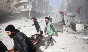  ?? (Bassam Khabieh/Reuters) ?? A WOUNDED WOMAN is carried on a stretcher after an air strike in the besieged town of Douma last week.