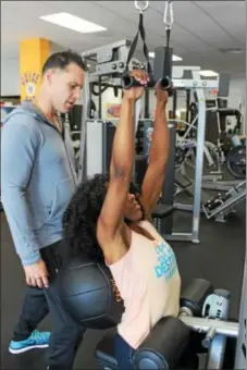  ?? PHOTOS BY MICHILEA PATTERSON — DIGITAL FIRST MEDIA ?? Ernie Groff, owner of I Am Fit Studios, trains Fabienne Daniel at the Sinking Spring location. Daniel is using a machine to work on her arm strength while Groff holds a medicine ball to her back.