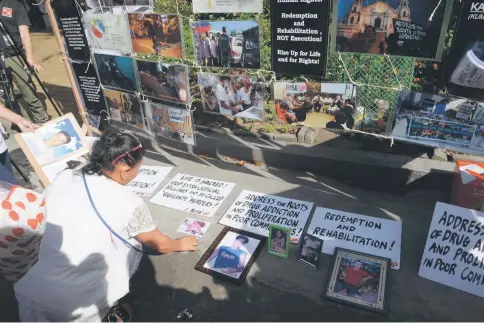  ??  ?? File photo shows a relative of a victim of extra-judicial killings in Duterte’s drug war arranging photograph­s of victims during a gathering on the grounds of a church in Manila. — AFP photo