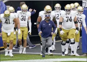  ?? THE ASSOCIATED PRESS FILE PHOTO ?? Notre Dame head coach Brian Kelly, center, leads the team on to the field for an NCAA college football game against Pittsburgh in Pittsburgh.