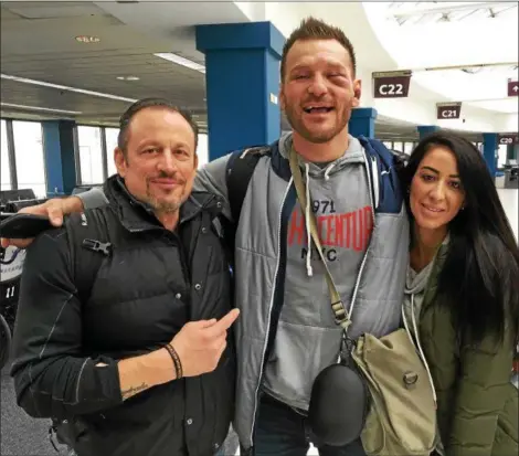  ?? MARK PODOLSKI - THE NEWS-HERALD ?? Stipe Miocic, with head coach Marcus Marinelli and wife Ryan, after arriving at Cleveland Hopkins Airport from Boston on Jan. 21.