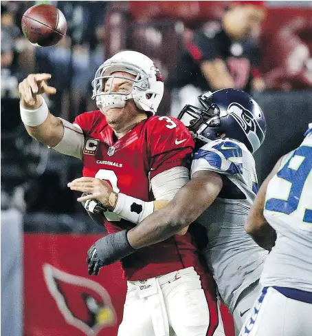  ?? — THE ASSOCIATED PRESS ?? Arizona Cardinals quarterbac­k Carson Palmer is hit by Seattle Seahawks defensive tackle Ahtyba Rubin as he throws Sunday in Glendale, Ariz. The game ended in a rare 6-6 tie.