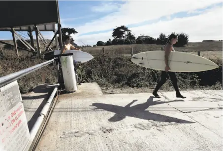  ?? Carlos Avila Gonzalez / The Chronicle 2014 ?? Surfers Taletha Derrington of Belmont (right) and Nick Nayfack of S.F. go around a gate blocking Martin’s Beach Road in 2014. The owner of the beach is fighting in court to beat back attempts to force him to reopen access to the public.