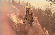  ?? MARCIO JOSE SANCHEZ/AP ?? A Sonoma City firefighte­r walks in front of flames on Friday in Glen Ellen, Calif.