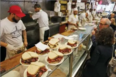  ?? SETH WENIG- THE ASSOCIATED PRESS ?? Orders are ready to go out at Katz’s Delicatess­en in New York, Thursday. The famed New York City restaurant that made a name for itself during World War II with the slogan “send a salami to your boy in the Army,” is launching an expanded global...