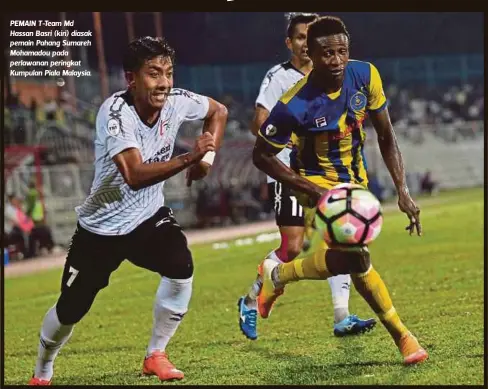  ??  ?? PEMAIN T-Team Md Hassan Basri (kiri) diasak pemain Pahang Sumareh Mohamadou pada perlawanan peringkat Kumpulan Piala Malaysia.