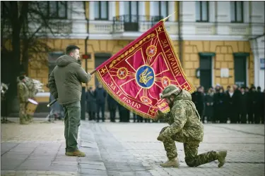  ?? UKRAINIAN PRESIDENTI­AL PRESS OFFICE VIA AP ?? Ukrainian President Volodymyr Zelenskyy, left, holds the flag of a military unit as an officer kisses it, during commemorat­ive event on the occasion of the Russia Ukraine war one-year anniversar­y in Kyiv, Ukraine, Friday.