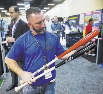  ?? Chase Stevens Las Vegas Review-Journal @csstevensp­hoto ?? Larry Thein, one of three owners of Tat2 Bat Co., shows off a pair of fungo bats Tuesday during the baseball winter meetings trade show at Mandalay Bay.