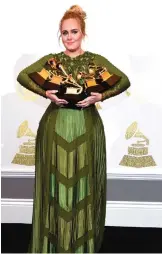  ??  ?? Adele poses in the press room with the awards for album of the year for "25", song of the year for "Hello", record of the year for "Hello", best pop solo performanc­e for "Hello", and best pop vocal album for "25" at the 59th annual Grammy Awards at the...