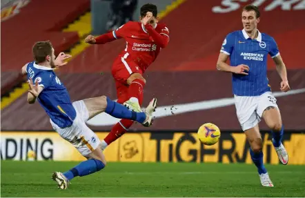  ?? — AFP ?? Quick reflexes: Brighton’s Adam Webster (left) blocking a shot by Liverpool’s Roberto Firmino (centre) during the English Premier League match at Anfield.