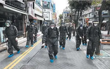  ?? CHUNG SUNG-JUN/GETTY ?? South Korean health measures: Health officials spray antiseptic solution Thursday outside stores in Incheon, South Korea, to prevent the spread of the coronaviru­s. South Korea has decided to relax restrictio­ns on eateries, fitness centers and other facilities in the wider Seoul area. South Korea’s new virus cases stayed below 200 for the 15th consecutiv­e day.