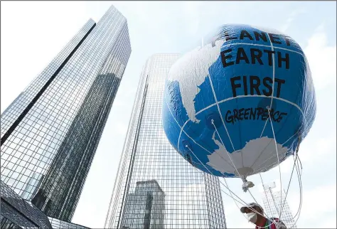  ?? (AP/dpa/Arne Dedert) ?? A demonstrat­or holds a balloon with the words “Planet Earth First” on Friday at the Fridays for Future central climate strike in Frankfurt, Germany, with Deutsche Bank headquarte­rs in background.
