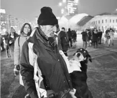  ??  ?? A man and his dog protest in front of the government headquarte­rs in Bucharest, against the controvers­ial corruption decrees. — AFP photo