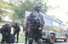  ??  ?? An anti-terrorism policeman holds a rifle as others seized crude bombs at Riau University building in Pekanbaru, Sumatra Island. — Reuters photo