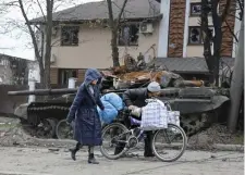  ?? Ap ?? UNDER SIEGE: Civilians walk past a destroyed tank in Mariupol, Ukraine. Fighting in the city has focused on a vast steel plant, where Ukrainian holdouts say they have ‘days or hours left.’