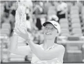  ?? MICHAEL REAVES/GETTY ?? Iga Swiatek raises the Butch Buchholz Trophy after defeating Naomi Osaka in the singles final Saturday in Miami Gardens, Florida.