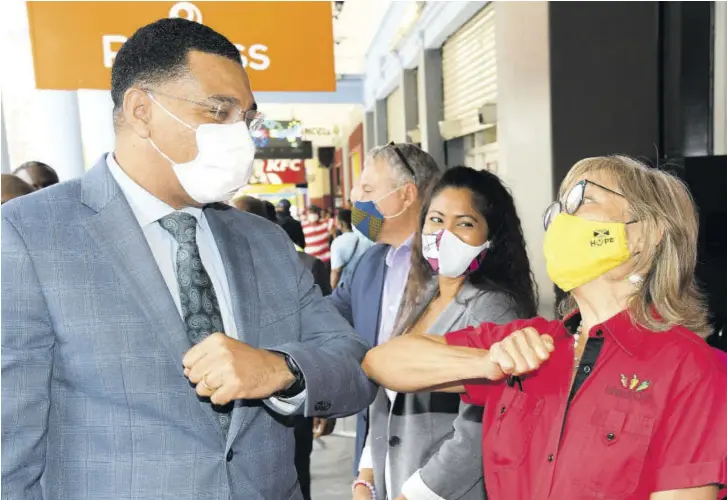  ??  ?? Prime Minister Andrew Holness is welcomed to the new Island Grill restaurant on King Street, downtown Kingston with an elbo bump by the chain’s founder and CEO Thalia Lyn. Enjoying the moment is Priscilla Sinanan, marketing manager, Island Grill.