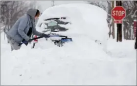  ?? ASSOCIATED PRESS ?? Chelse Volgyes clears snow from her car in Erie. The city is trying to dig out of a record snowfall of 65 inches this week.