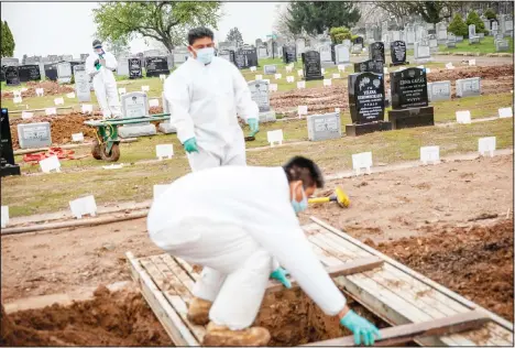  ?? (AP) ?? Rabbi Shmuel Plafker (rear), finishes a prayer during the burial service for David Tokar as gravedigge­rs prepare a plot for the next burial at Mount Richmond Cemetery in the Staten Island borough of New York, April 8. When Plafker arrives at the cemetery, it’s buzzing: Vans pulling in with bodies aboard, mounds of dirt piling up as graves are dug open, a line of white signs pressed into the ground marking plots that are newly occupied. Some of the few signs of life in this anguished city are coming from those tending to the dead.