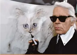  ?? Jens Kalaene/ AFP ?? Karl Lagerfeld com uma pintura da gata Choupette que deverá herdar parte de sua fortuna