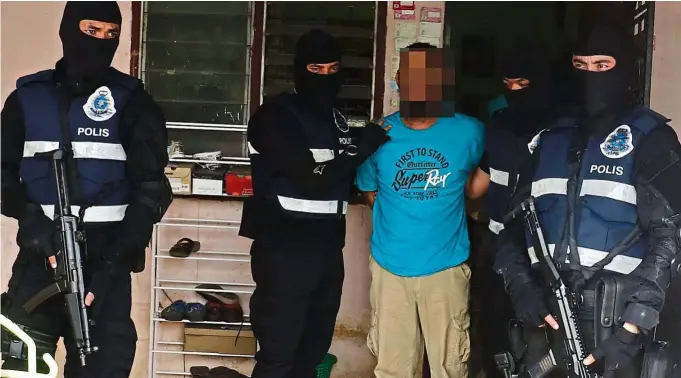  ??  ?? End of the road: Bukit Aman Special Branch Counter Terrorism Division officers picking up a suspected militant.